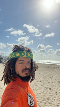 a man with dreadlocks taking a selfie on the beach